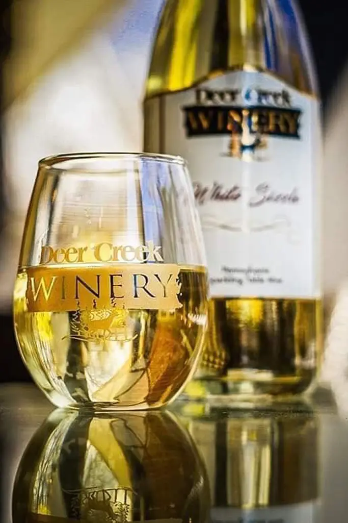 deer creek winery wine glass and bottle with white wine in it