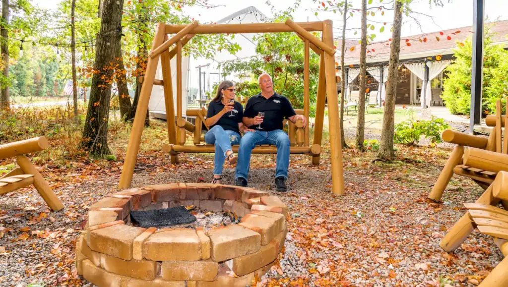 Spend Your Summer Getaway at Brooks Estate in Pennsylvania Wine Country denis and rhonda brooks sitting at the outside area by firepits at brooks estate