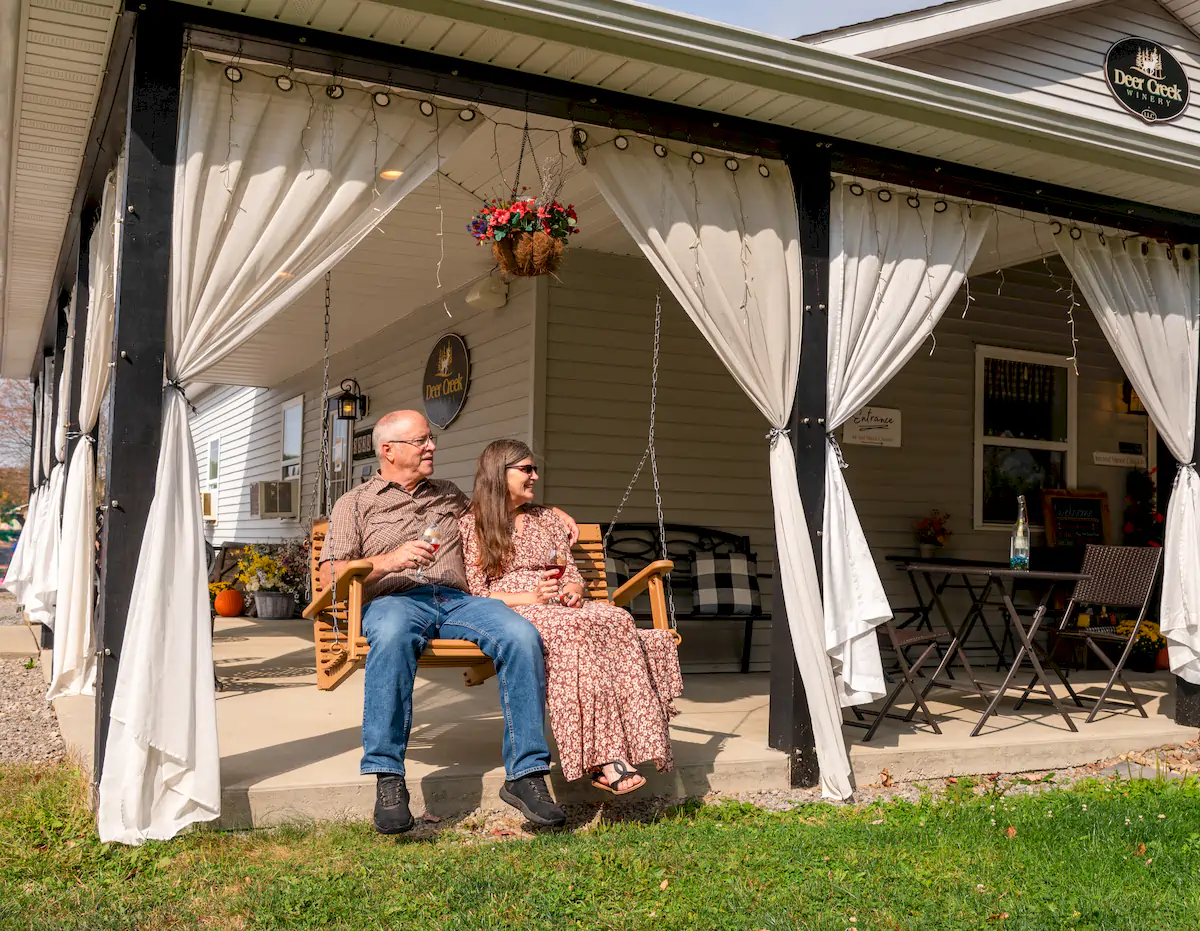 Compare Estates denis and rhonda brooks sitting in the swing on vino's den porch at brooks estate