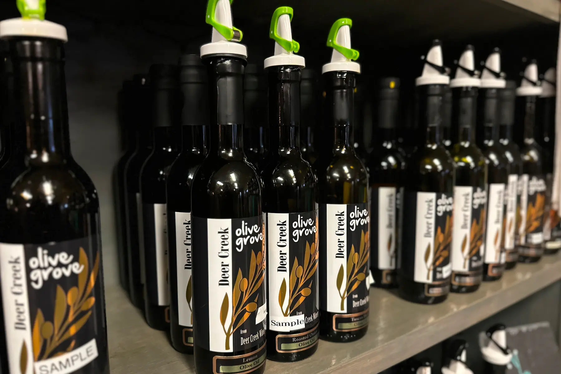 Deer Creek Olive Grove olive oils on display in the tasting room — Lemon, Roasted Onion, and Tuscan Herb olive oils available to sample at Deer Creek Winery