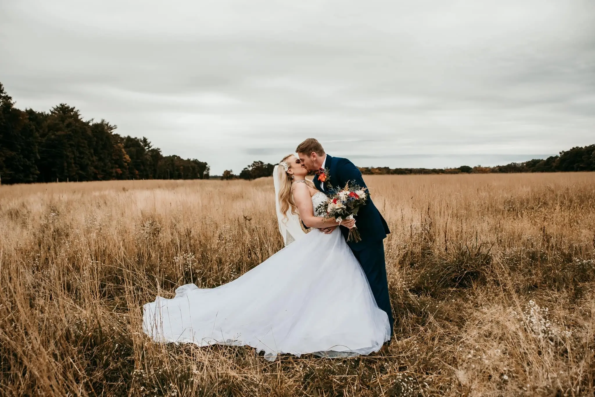 married couple kissing in field at deer creek winery
