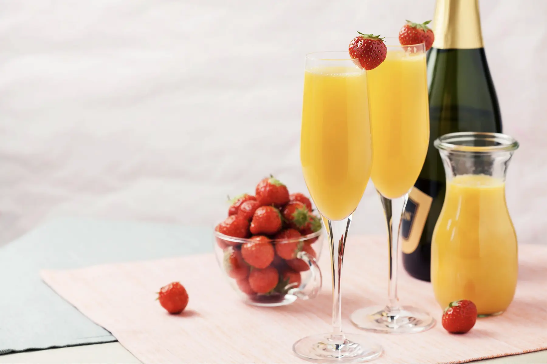 Two mimosa champagne glasses with strawberries and orange juice for Mother's Day mimosa bar at Deer Creek Winery
