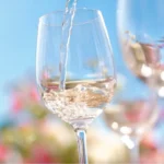 Summer Breeze Sangria being poured into a wine glass on a sunny summer day